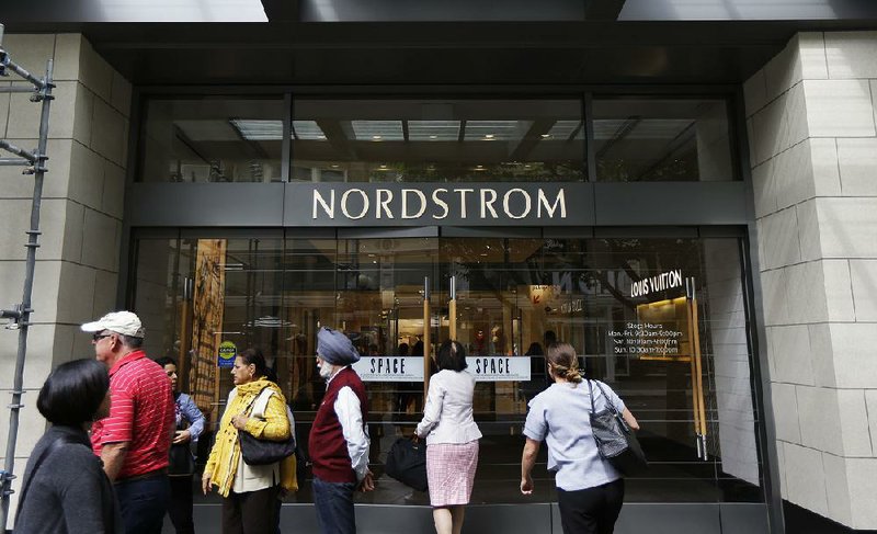 People stand outside a Nordstrom’s flagship department store in downtown Seattle in September. Survey results released Thursday said Americans will increase spending by 6 percent in November and December. 