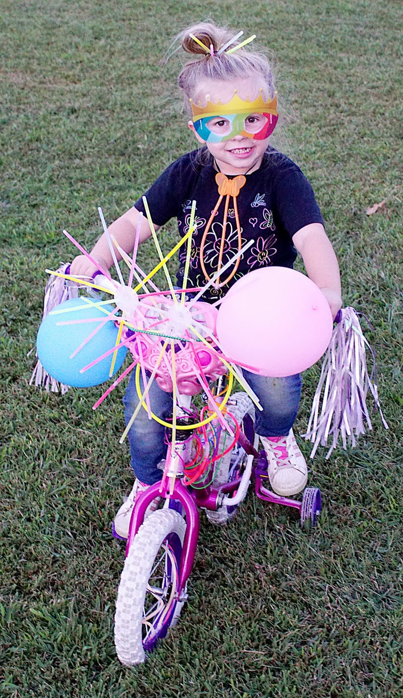 Photo by Randy Moll Peighton Goodman, 3, was ready to ride just before the Gentry glow ride event on Saturday night. Young and old decorated their bicycles, added glow sticks and rode east and west down Main Street during the Gentry Chamber of Commerce sponsored event.
