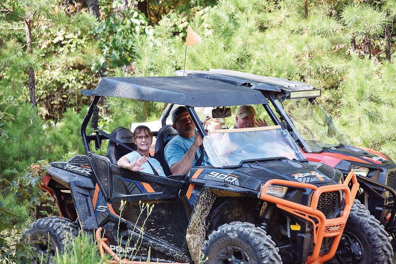 Stacia and Zach Harmon, left, ride alongside Johnny Sowell and his son, Kyler, on the trails in Fairfield Bay.
