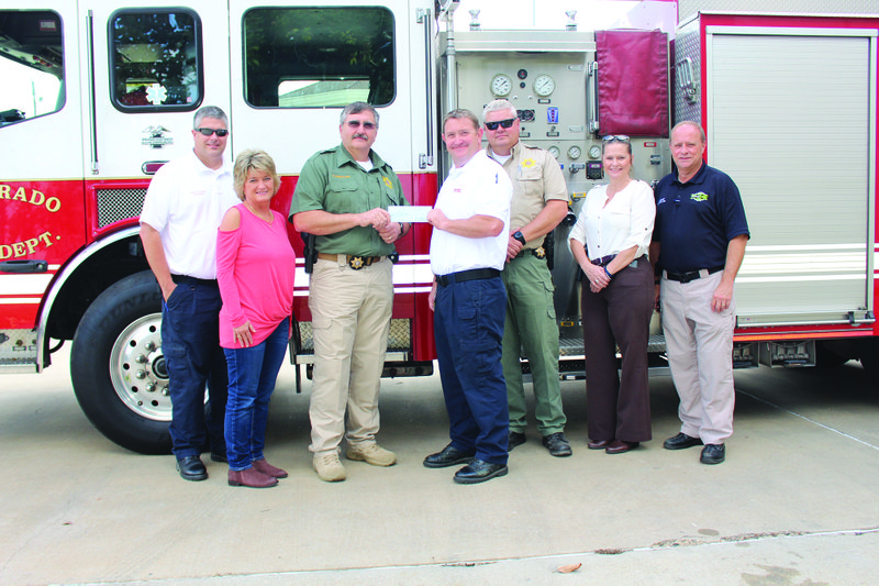 Check presentation: Chief Deputy Charlie Phillips presents Assistant Fire Chief Jesse McKinnon a check from the Union County First Responders Foundation Thursday for his child Braden. From left, Assistant Fire Chief Jason Evans, Jody Cunningham of Union County Judge's Office, Chief Deputy Phillips, Assistant Chief McKinnon, Captain Richard Mitcham, Investigator Tammie Martin and Ken Kelly, CEO of ProMed. Lt. Trey Sewell also received a check from the organization, but was unable to attend the presentation.  