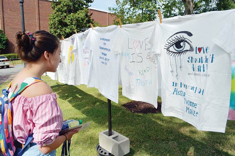 Emily Busby, 18, of Jacksonville looks at a display Wednesday at the University of Central Arkansas that contains T-shirts representing women, men and children killed by domestic violence. The Clothesline Project was brought to UCA by the Women’s Shelter of Central Arkansas in Conway. Executive Director Carrie Curtis said the national trend is that people ages 18-24 are the most abused. “Our hope is to make an impact now,” she said.