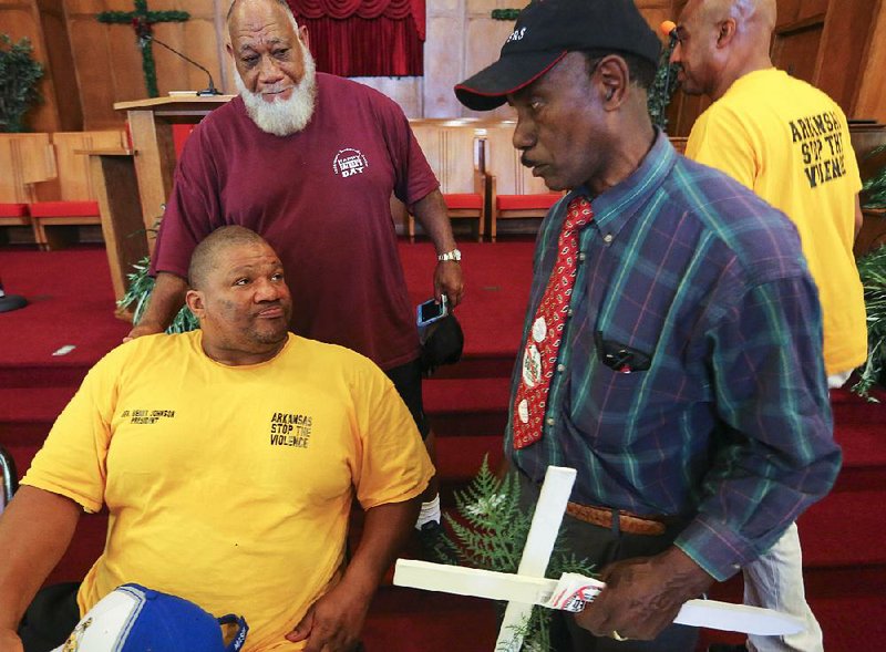 Benny Johnson (sitting, left), founder and president of Arkansas Stop the Violence, and supporters Richard Anderson (top left) and Earnest Franklin, discuss an incident with police Monday night that has Johnson calling for the resignation of Little Rock Police Chief Kenton Buckner and City Manager Bruce Moore.