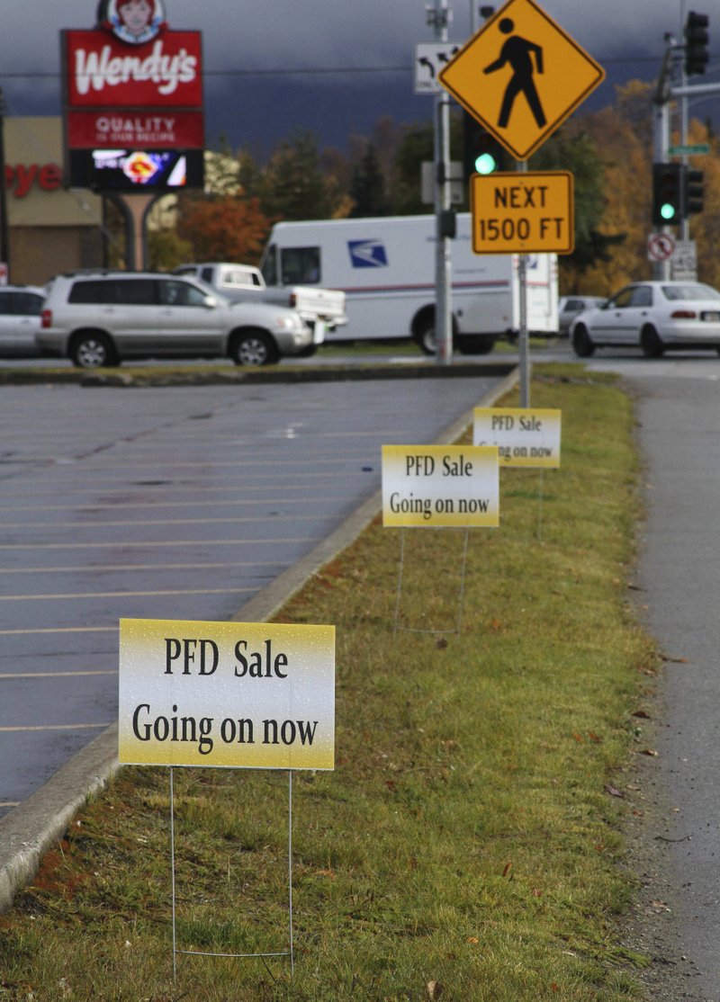 Signs meant to entice recipients of payouts from the state's Permanent Fund Dividend Division, also known as PFD, advertise a sale in Anchorage, Alaska, Wednesday, Oct. 4, 2017. Nearly every Alaskan will wake up $1,100 richer on Thursday, thanks to this year's payout from the state's oil wealth investment fund. The distribution from the Alaska Permanent Fund is essentially free money for residents, who already don't pay a state income tax or statewide sales tax. (AP Photo/Mark Thiessen)