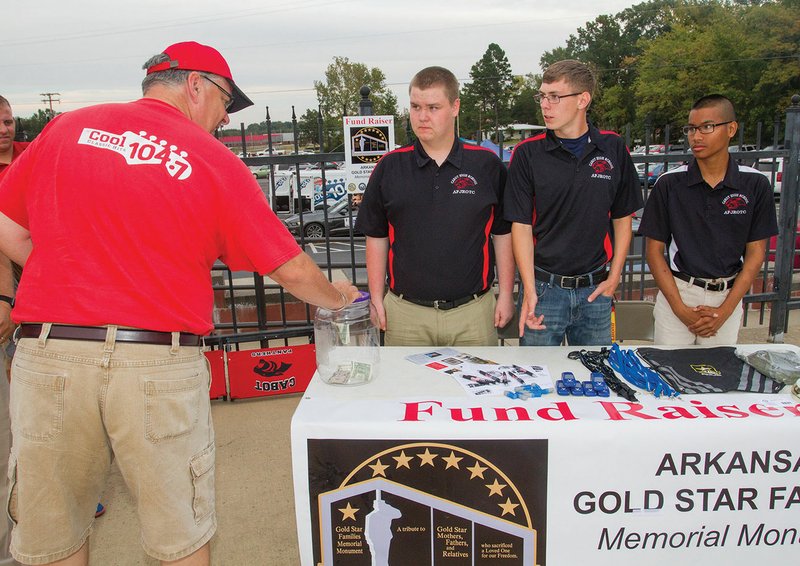 Robert Morton of Searcy makes a donation at the Cabot High School Air Force JROTC’s Gold Star Families Memorial Monument fundraiser booth. From left, Nathan Claunch, Brenon Brock and Kameron Evans tell football-game patrons about their cause.