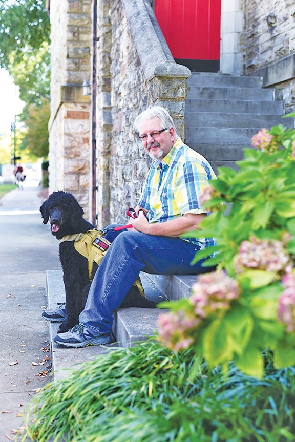 Russell Steed and his dog, Jasper, sit on some steps in front of a church in downtown Little Rock. Steed served in the U.S. Navy from 1982 to 1992 before sustaining an injury aboard the USS Carl Vinson. He said Jasper has helped him tremendously with his post- traumatic stress disorder. 