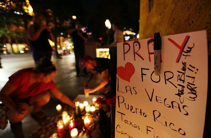 Pausing to remember and reflect, people surround a memorial set up for victims and survivors of the mass shooting in Las Vegas on Tuesday. The deadliest mass shooting in modern U.S. history comes just after a series of natural disasters in Texas, Florida and Puerto Rico and an earthquake in central Mexico, and has people — secular and of faith — asking why others suffer.