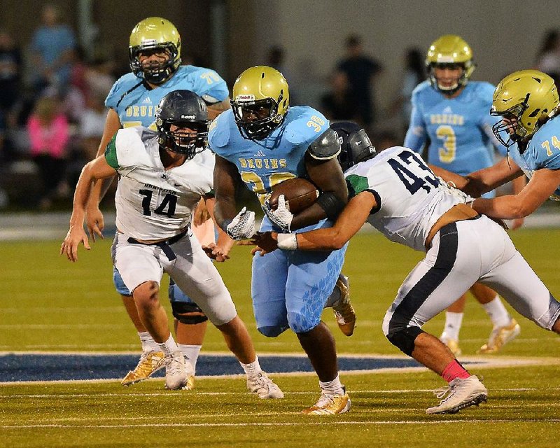 Pulaski Academy running back Isiah Woods (center) runs through a tackle by Little Rock Christian linebacker Grant McElmurry (43) during Friday’s game at Joe B. Hatcher Stadium in Little Rock.