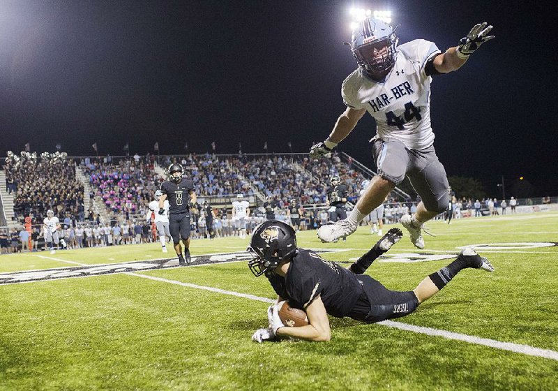 Springdale Har-Ber linebacker Trevor Alderson (44) leaps over Bentonville quarterback Nathan Lyons during Friday night’s game in Bentonville. The Tigers defeated the top-ranked Wildcats 24-21.