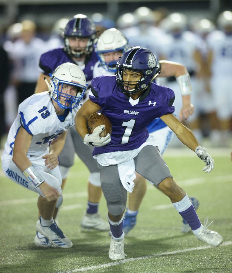 Fayetteville receiver Cody Gray (1) turns upfield after making a catch as he is pursued by Rogers linebacker Jarrett Bush during the Bulldogs’ 52-14 victory over the Mountaineers on Friday at Harmon Stadium in Fayetteville. For more high school football photos, visit arkansasonline.com/galleries.