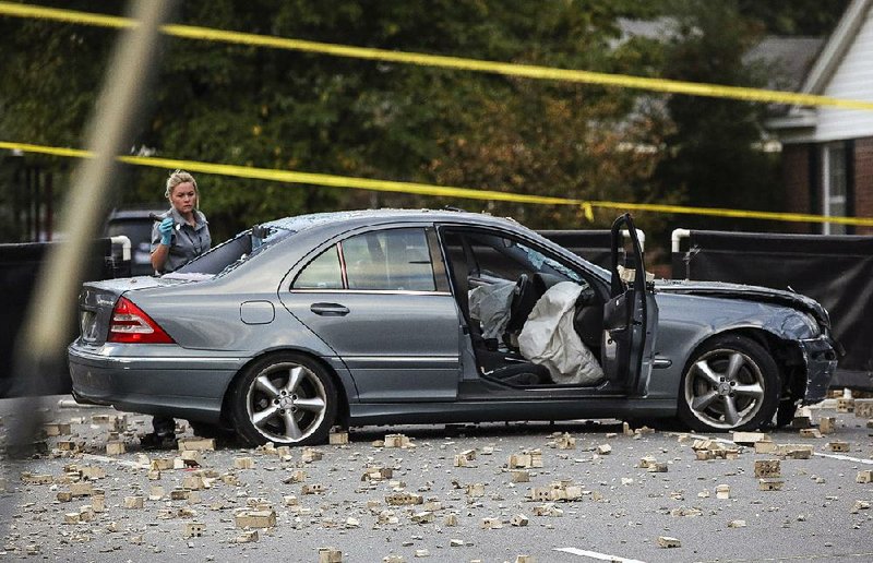 A crime scene technician collects evidence on the car involved in an Oct. 7, 2017, crash and shooting in a University Avenue parking lot in Little Rock. 