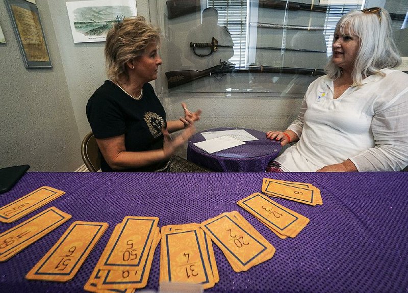 Numerologist Cheryl Waldmer (right) does a reading Saturday for Elizabeth Thomas of White Hall at the paranormal expo in Little Rock. The event continues today. 