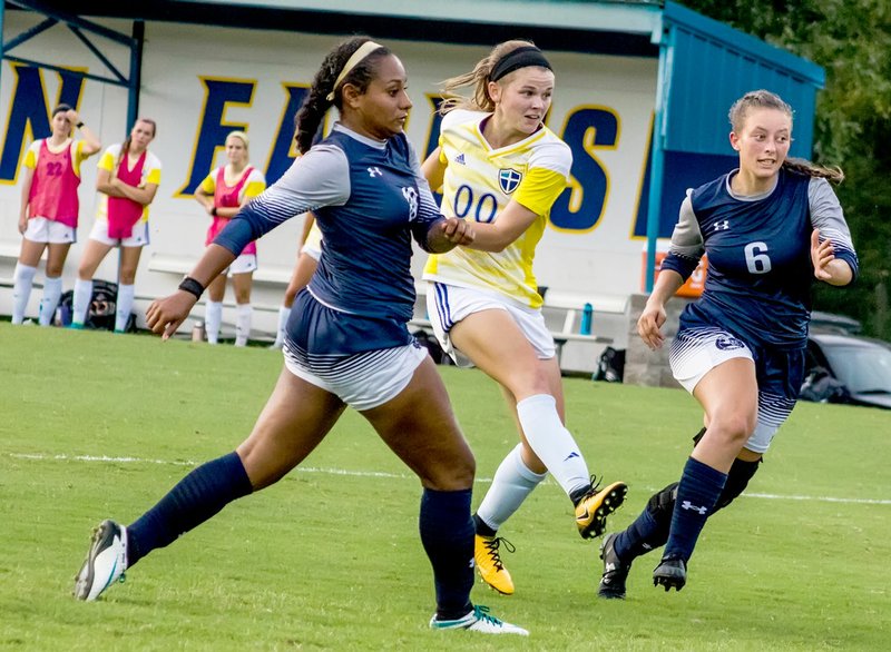 Photo courtesy of JBU Sports Information John Brown University senior Hannah Poor splits a pair of defenders during Thursday's match against Wayland Baptist (Texas).