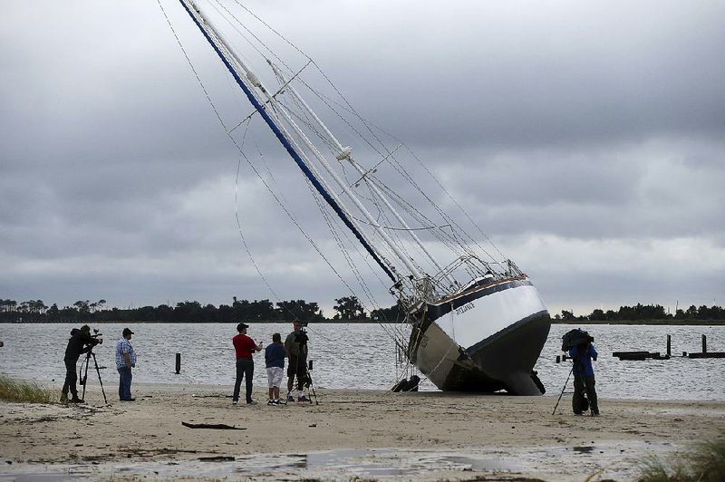 News crews film a sailboat that washed ashore along the Gulf of Mexico on Sunday in Biloxi, Miss., in the aftermath of Hurricane Nate.