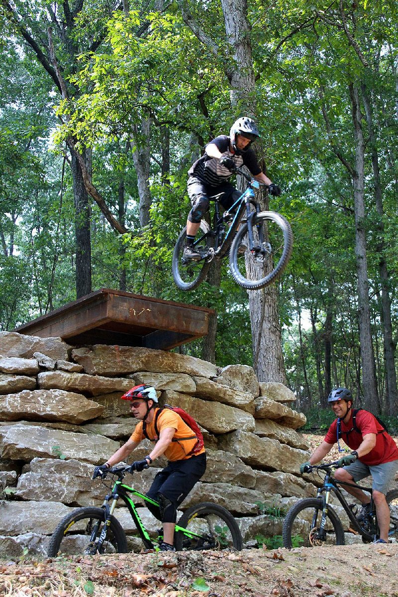 Andy Wiseman of Bella Vista soars off “Drop the Hammer” Sept. 17, over the heads of Mike Berry and Chris Thompson, both from Bentonville, during the Coler Enduro at Coler Mountain Bike Preserve.