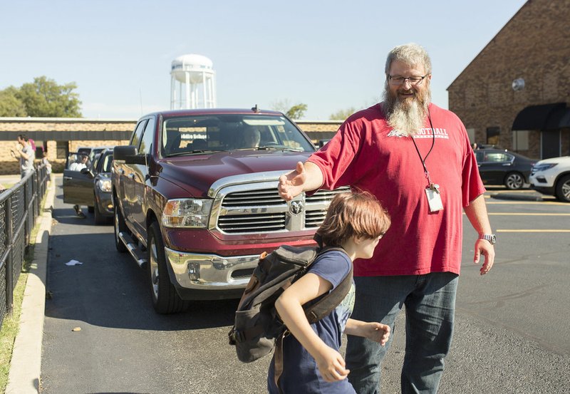 Rodney Robinson of Centerton helps a student cross the street on Friday at Old High Middle School in Bentonville.