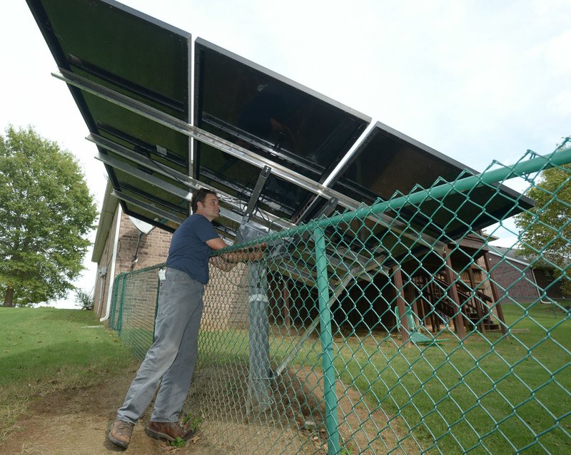 Flint Richter, owner of Richter Solar Energy in Fayetteville, checks voltage produced by a solar panel array Thursday at a client’s home in western Fayetteville. Fayetteville released a first draft of its Energy Action Plan, which calls for the city to run on 100 percent clean energy by 2050.