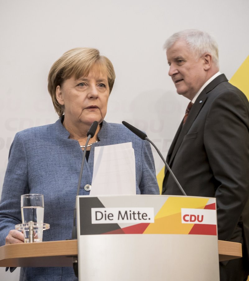 German Chancellor Angela Merkelof the German Christian Democratic Union, CDU, left, and Bavaria's State Governor Horst Seehofer, right, of the Christian Social Union, CSU, arrive for a news conference in Berlin, Monday, Oct. 9, 2017. Germany's conservative parties say they have agreed on a law limiting the number of migrants allowed to enter the country every year. 