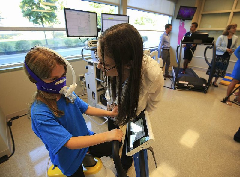 Eva Diaz checks on Alice McMains, 6, as she rides a stationary bike Tuesday at the Laboratory for Active Kids and Families at Arkansas Children’s Hospital in Little Rock.