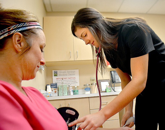 Janelle Jessen/Herald-Leader Senior Hadlee Hollenbeck, right, took a patient's blood pressure at the Siloam Springs Medical Center. Hollenbeck is working at the clinic as part of the Siloam Springs High School's community internship program.