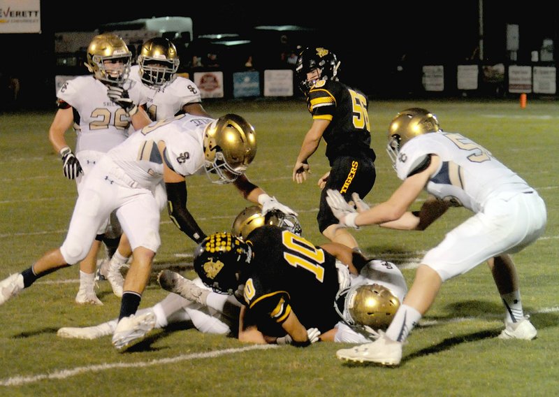 MARK HUMPHREY ENTERPRISE-LEADER A Shiloh Christian defender reaches down to unlatch the helmet of Prairie Grove quarterback J.D. Elder after a 5-yard run. He was flagged for a 15-yard personal foul penalty and Elder stayed in the game, throwing a 30-yard touchdown pass to Stone Bryant three plays later to put the Tigers up 20-7. Prairie Grove defeated Shiloh Christian, 35-21, Friday to stay unbeaten in conference play.