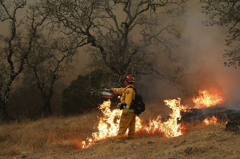California firefighter John Clays of San Diego lights a backfire Wednesday in Sonoma County, Calif., to starve a huge wildfire of fuel as crews struggle to get containment. 