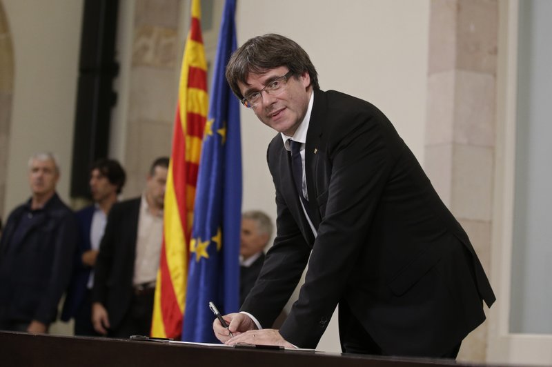 Catalan regional President Carles Puigdemont signs an independence declaration document after a parliamentary session in Barcelona, Spain, Tuesday, Oct. 10, 2017. Puigdemont says he has a mandate to declare independence for the northeastern region, but proposes waiting &quot;a few weeks&quot; in order to facilitate a dialogue. (AP Photo/Manu Fernandez)