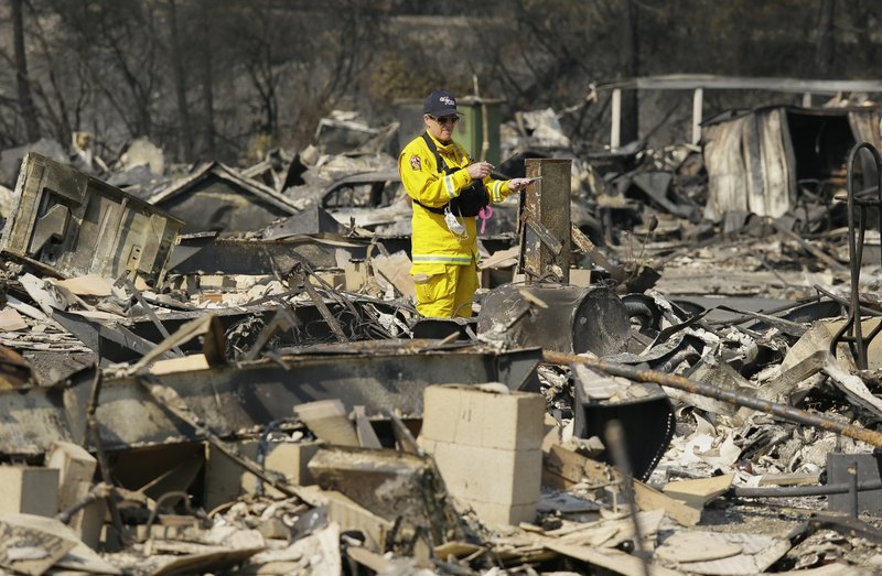 A Cal Fire official looks out at the remains of the Journey's End mobile home park Wednesday, Oct. 11, 2017, in Santa Rosa, Calif.  Blazes burning in Northern California have become some of the deadliest in state history. (AP Photo/Eric Risberg)