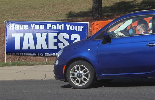 The Sentinel-Record/Richard Rasmussen TIME TO PAY: A motorist passes a sign near the intersection of Lakeshore Drive and Higdon Ferry Road on Wednesday reminding residents that their real and personal property taxes are due Monday.
