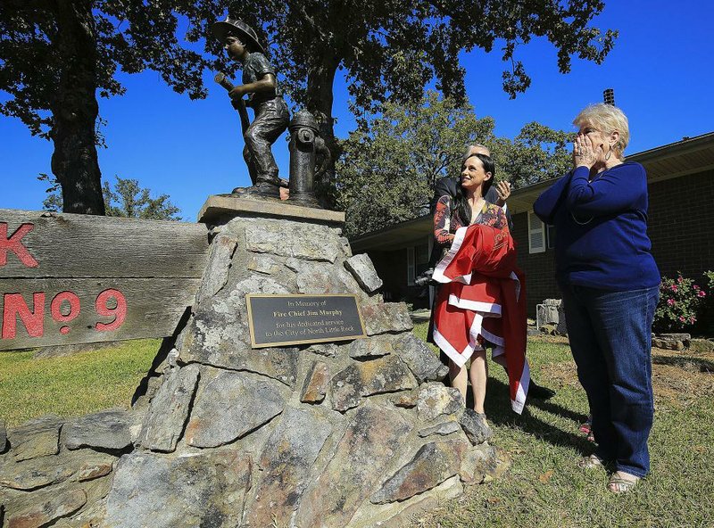 Kit Murphy (right) and her niece Arian Clute look at a statue and plaque honoring Murphy’s late husband Jim Murphy, a former North Little Rock fire chief, on Thursday during a ceremony at city Fire Station No. 9. 