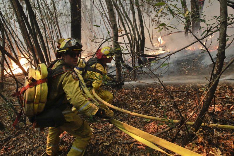 Firefighters put out a hot spot from a wildfire Thursday, Oct. 12, 2017, near Calistoga, Calif. Communities in wildfire-prone Northern California have an array of emergency systems designed to alert residents of danger: text messages, phone calls, emails and tweets. But after days of raging blazes left at least 23 dead, authorities said those methods will be assessed after some residents complained those warnings never got through. 