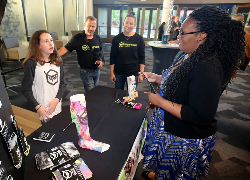 NWA Democrat-Gazette/DAVID GOTTSCHALK Sofi Overton (from left), 12, with Wise Pocket Products, stands with her parents John and Brandy Overton Thursday as she describes her socks and leggings with pockets to Tamica Stubblefield, with Cox Business, during the Get Started NW Arkansas event at the Walton Arts Center in Fayetteville. Overton is one of five local startups that gave a quick pitch for their business in front of a panel of judges, each trying to win $11,500 in money and support.