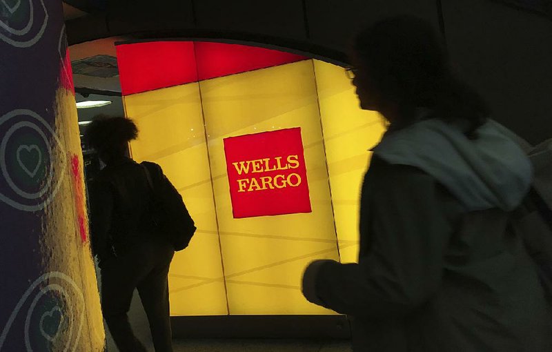 Commuters pass a Wells Fargo ATM in New York’s Penn Station in this file photo. Wells Fargo said Friday that it earned $4.6 billion in the third quarter.