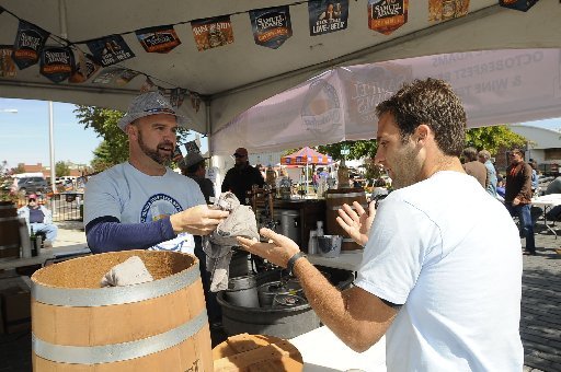 File photo: Ben Moore, left, hands a shirt to Drew Sadler of Rogers after Sadler registered for a contest on Saturday Oct. 4 2014 during the Oktoberfest and Craft Beer Experience in downtown Rogers. The event featured music, a variety of craft beers and grilled bratwurst meals.