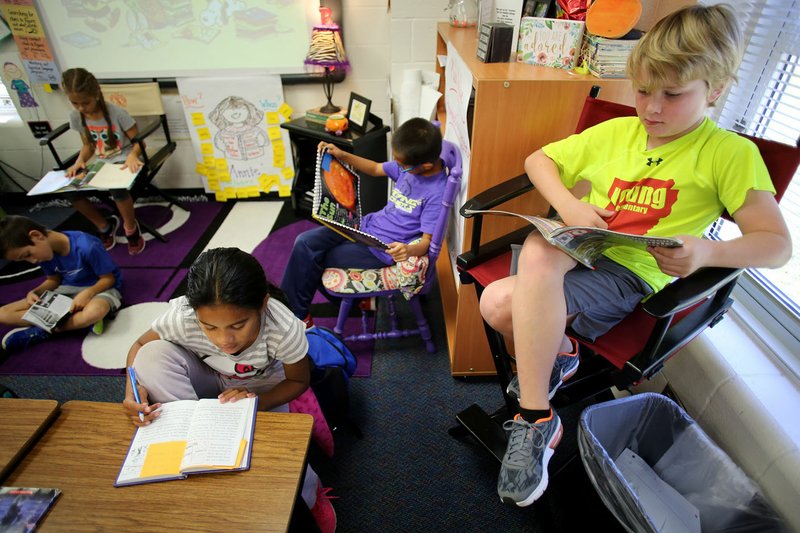 Griffin Kelley (from right), Eric Wang and Sonia Bithen, all third-graders in Karen Swalley’s class at Bernice Young Elementary School, read Friday as part of their nonfiction unit of study at the Springdale school. The school benefits from the Arkansas School Recognition Program. The school received about $275,000 since the program started in 2013 and used much of its reward money on books for classroom libraries.