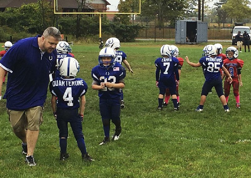 John Galligan (left) directs players during a Rookie Tackle youth football game in Islip, N.Y. USA Football has introduced the program which is played on a 40-yard field with as few as six players to a side.