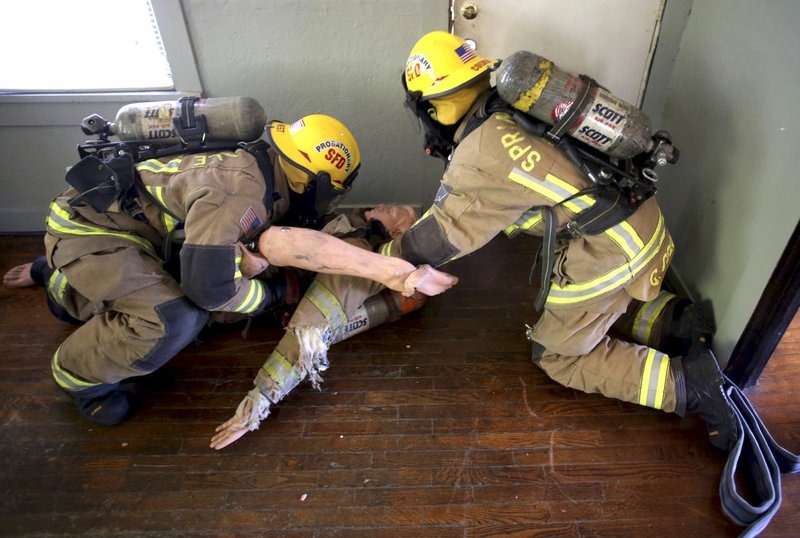 Andrew West (left) and Chase Colvin, both probationary firefighters with the Springdale Fire Department, participate Friday in a Mayday Rapid Intervention Team drill rescuing a firefighter down at an abandoned house in Springdale. The Springdale Fire Department is looking to build a few more fire departments.