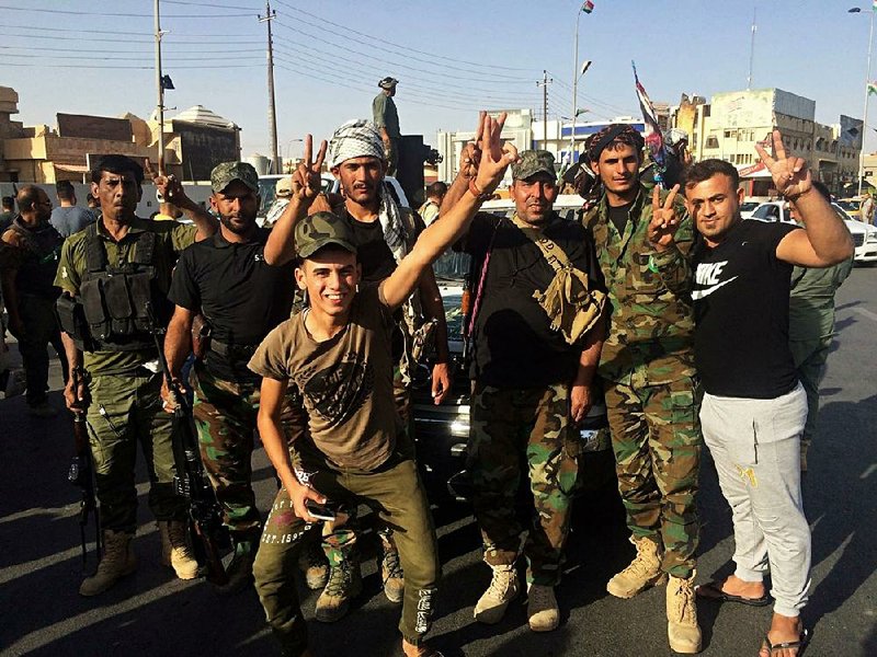 Iraqi security forces and volunteers celebrate Monday in front of Governorate Council Building in Kirkuk, Iraq.