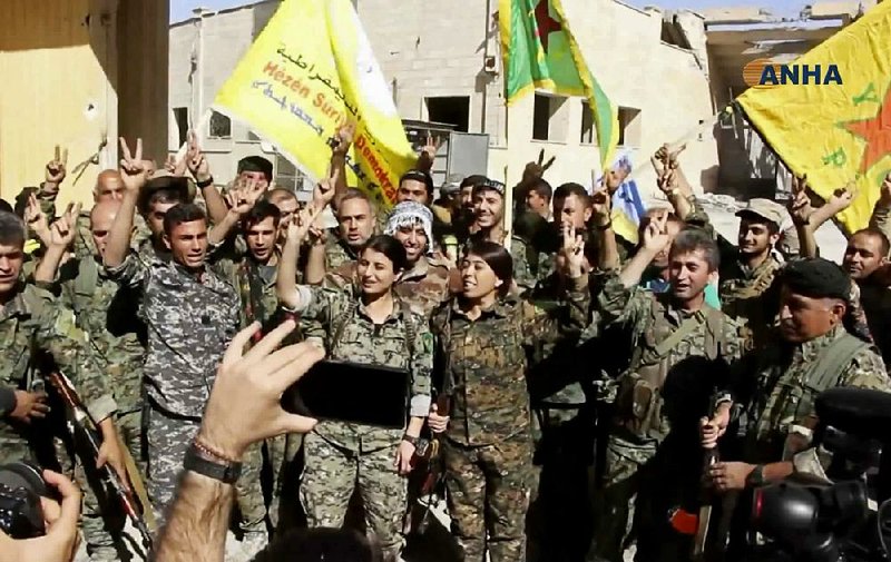 This frame grab from video released Tuesday and provided by Hawar News Agency, a Syrian Kurdish activist-run media group, shows fighters from the U.S.-backed Syrian Democratic Forces celebrating in Raqqa, Syria.  