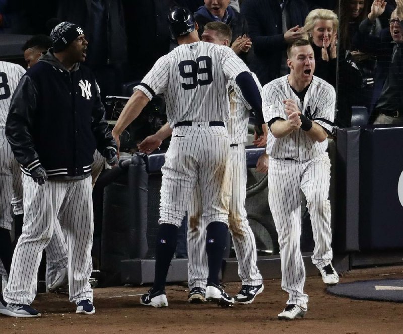 Todd Frazier (right) of the New York Yankees celebrates after Aaron Judge (99) scored in the eighth inning of the Yankees’ 6-4 victory over the Houston Astros in Game 4 of the American League Championship Series on Tuesday. The Yankees scored two runs in the seventh inning and four in the eighth as they evened the best-of-seven series at 2-2.