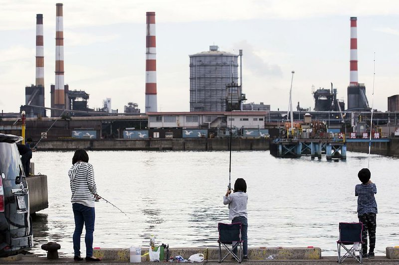 People fish across from a Kobe Steel Ltd. plant in Kakogawa, Hyogo, Japan on Saturday. The company said Tuesday that it is cooperating with the U.S. Department of Justice in an investigation of claims that it falsified certifications on the strength and durability of some of its metals going back to 2007. 