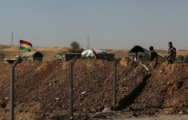 Kurdish security forces stand guard Tuesday in defensive positions on the outskirts of Irbil, Iraq. 