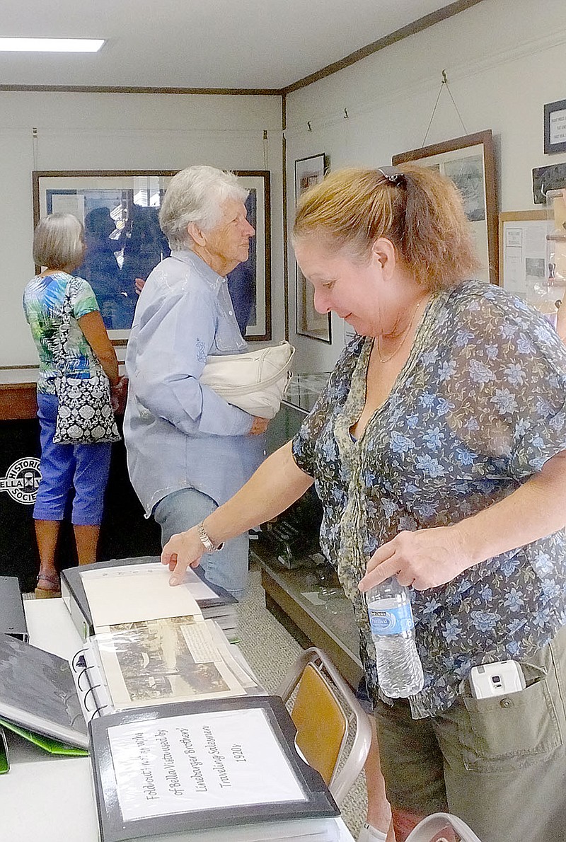 Lynn Atkins/The Weekly Vista Kathy Cox looks through one of the many scrapbooks on display at the Bella Vista History Museum during the annual open house last week. Cox promised to donate some family items that help tell the history of one marketing effort devised by John Cooper in the 1970s.
