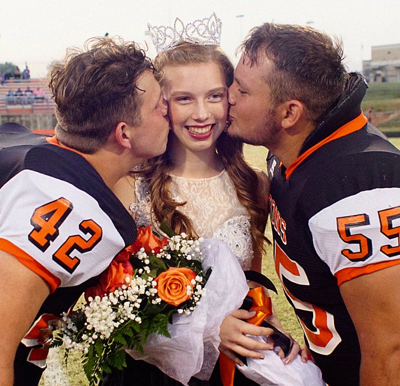 Photo by Randy Moll Colton Grimes and Kenton Tajchman kissed Hailee Gerner after she was crowned Gravette High School homecoming queen at ceremonies on the field at Lion Stadium on Friday night.