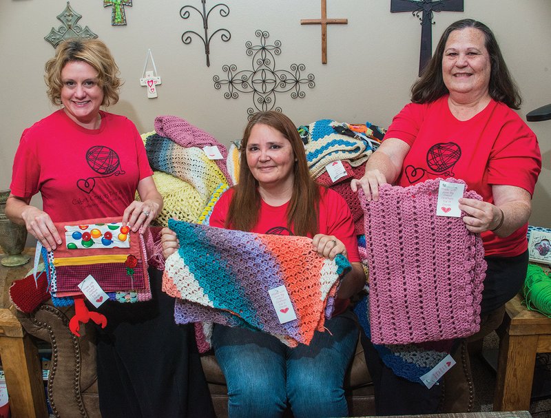 Kim Jasmin, from left, Rena Edwards and Alisa Branigan, members of Cabot Crafters for a Cause, hold up some of their creations. The group meets once a month and regularly donates handmade goods to people in need.