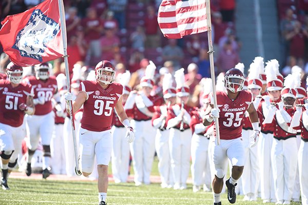 Arkansas defensive lineman Jake Hall (95) and linebacker Dwayne Eugene (35) carry flags onto the field prior to a game against New Mexico State on Saturday, Sept. 30, 2017, in Fayetteville. 