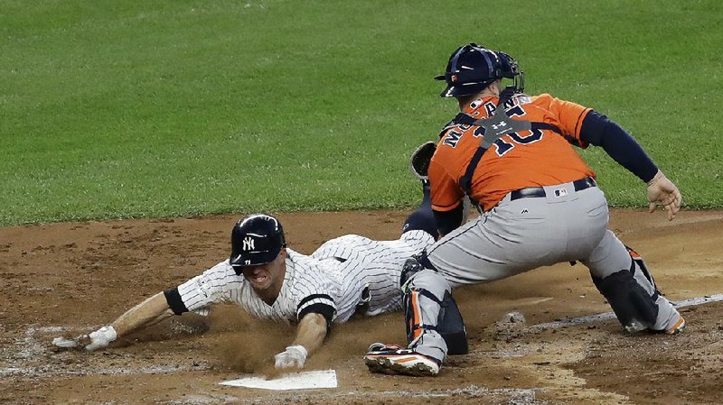 Brett Gardner of the New York Yankees slides past Houston Astros catcher Brian McCann to score in the third inning of the Yankees’ 5-0 victory Wednesday in Game 5 of the American League Championship Series. New York leads the series 3-2. 
