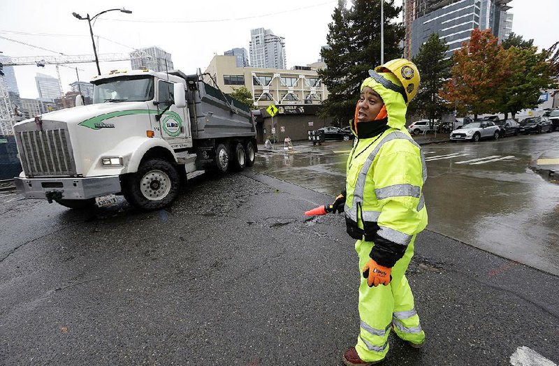 A construction worker directs traffic around a construction site near Amazon’s headquarters on Tuesday in Seattle. Today is the deadline for cities to submit bids for Amazon’s second headquarters development. 
