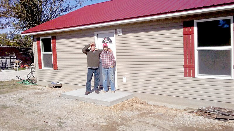 Photo submitted Ed Tuomala and his uncle. Jimmy Grife, stand on the doorstep of their new home, built by the Goodman community.