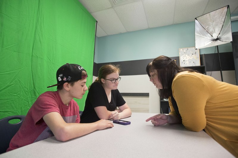 NWA Democrat-Gazette/BEN GOFF  @NWABENGOFF Oliver Chapracki and Mackenzie Allen, both eighth-graders, try different apps Thursday for editing video for morning announcements with help from teacher Lily Welch during a fall break camp for students at the Arkansas Arts Academy in Rogers.