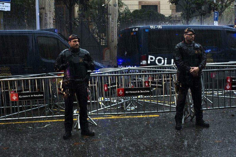 Catalan police officers cordon off the area Thursday as demonstrators gather at the gates of the Spanish government offices in Barcelona to protest the imprisonment of civil-society leaders. 